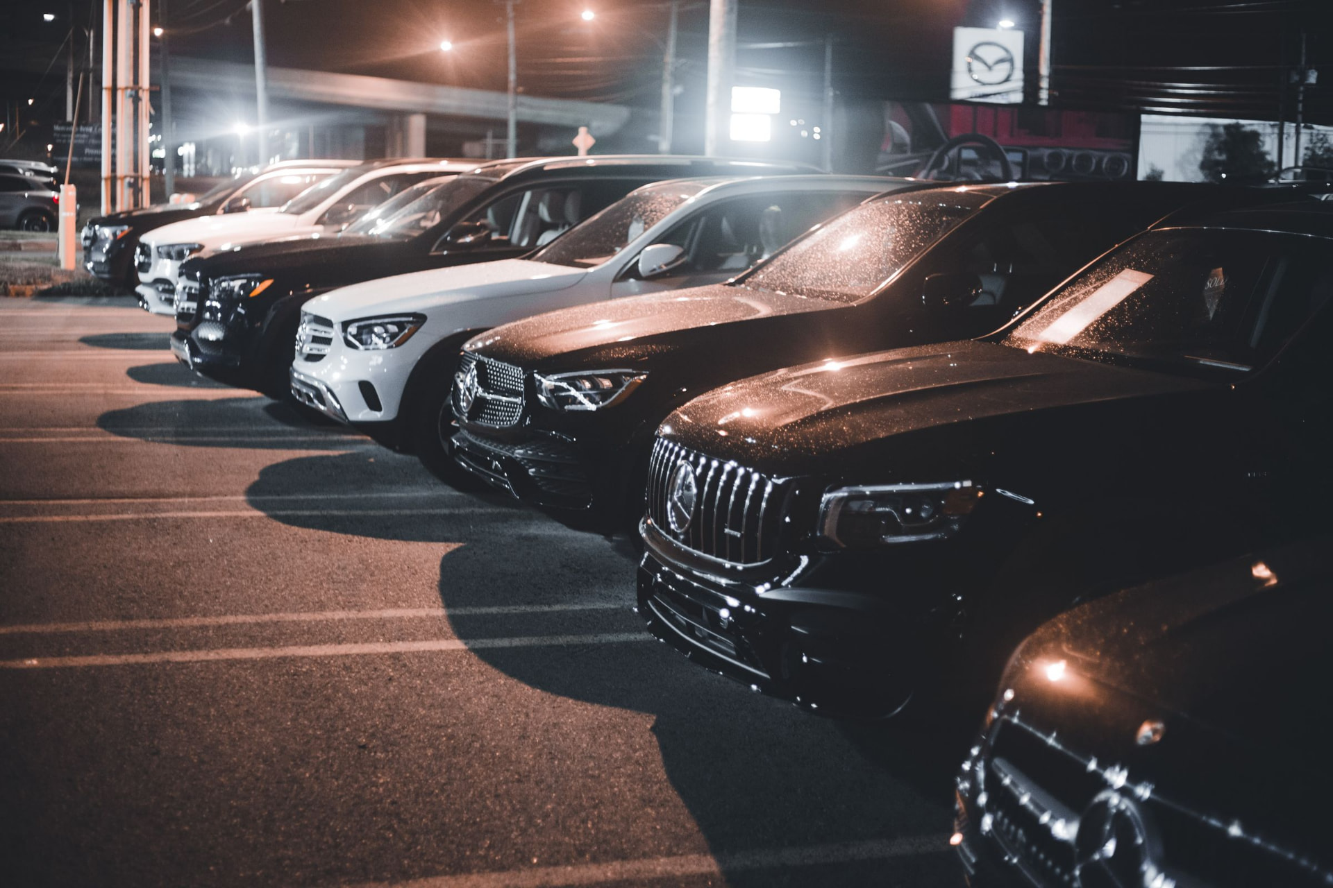 Lineup of luxury vehicles parked together at night under city lights